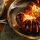 Roasted stuffed pumpkin sliced down the middle sitting in a skillet on top of a wooden table